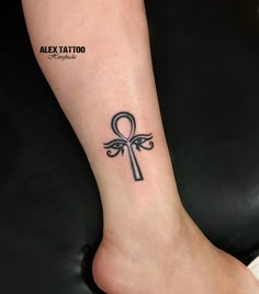 a tattoo on the foot of a woman with an egyptian cross and an olive leaf