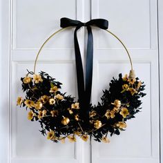 a black wreath with gold flowers hanging on a white door