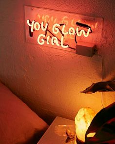 a bed room with a light that says you glow girl on the wall next to it