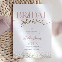 a white and gold bridal shower card on a wicker basket with pink ribbon