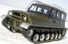 an army green vehicle is parked in the snow with wheels on it's tires