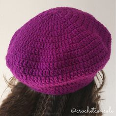 a woman wearing a purple crochet hat with her hair in the back view