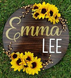 a wooden sign with sunflowers and the word emma lee painted on it's side