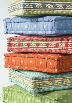 several pillows stacked on top of each other in different colors and patterns, all folded together