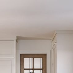 an empty kitchen with white cabinets and wooden doors, along with a black stove top oven