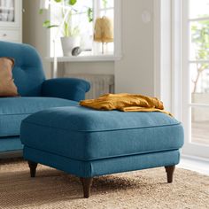 a blue ottoman sitting on top of a rug in a living room next to a chair