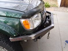 the front end of a green truck parked next to a blue toolbox and wrench