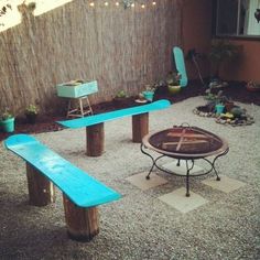 two blue benches sitting next to each other near a table and bench in the middle of a yard