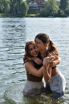 two young women are hugging in the water