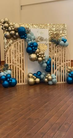 blue and silver balloons are on the floor in front of a white gate with gold trimmings