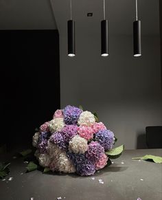 a bouquet of flowers sitting on top of a table next to three lights hanging from the ceiling