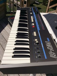 an electronic keyboard sitting on top of a wooden deck