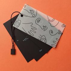 three pieces of paper with black and white designs are on an orange surface, next to each other