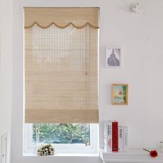 a room with a window covered in blinds and pictures on the wall behind it,