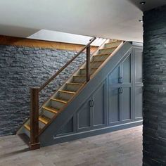 an empty room with stone walls and wooden stairs in the center, next to a brick wall