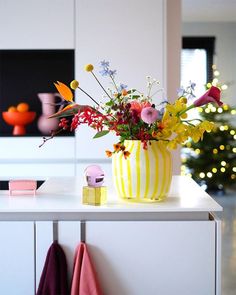 a vase filled with lots of flowers on top of a white counter next to a christmas tree