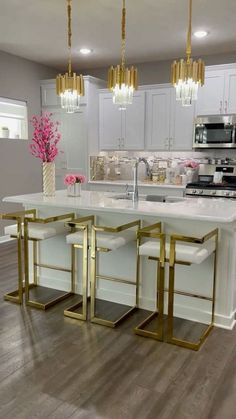 a kitchen with white cabinets and gold trim on the counter tops, along with an island in the middle