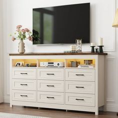 a flat screen tv mounted on top of a white dresser