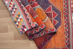 three different colored rugs laying on the floor next to each other, one with an orange and blue design