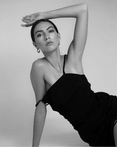 a black and white photo of a woman in a dress with her arms behind her head