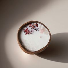 a coconut shell filled with milk and strawberries next to a shadow on a white surface