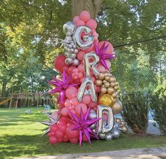 a large balloon tree with the word g r d spelled out in silver, pink and gold balloons