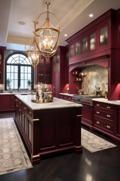 a large kitchen with red cabinets and marble counter tops, along with a chandelier hanging from the ceiling