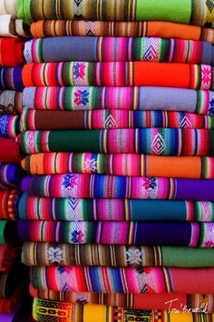 many colorful fabrics are stacked on top of each other