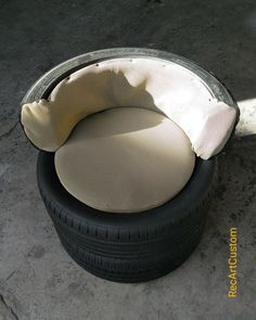 an old tire is sitting on the ground next to a cushion that looks like a dog bed