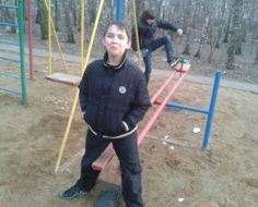 two young boys playing on a playground in the park, with one boy holding onto a rope