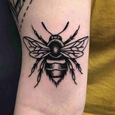 a black and white bee tattoo on the arm