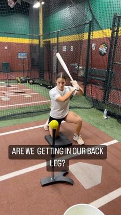 a woman holding a tennis racquet standing on top of a base ball field