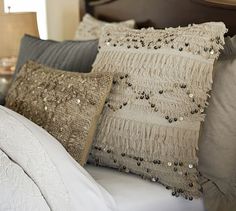 a bed topped with lots of pillows next to a night stand