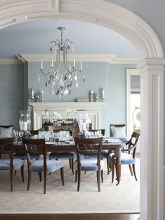 a dining room table with blue chairs and a chandelier hanging from the ceiling