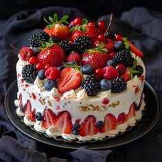 a cake with berries, strawberries and blueberries on top sits on a black plate