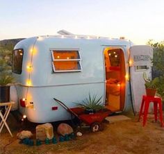 an rv is parked in the dirt with its door open and lights on it's side