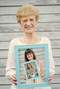 an older woman holding up a blue frame with a picture of her daughter on it