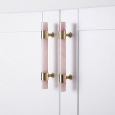 two pink glass door handles on white cupboards