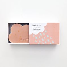 a soap bar in a pink box on a white surface with a cloud and rain design