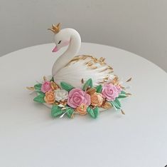 a swan figurine sitting on top of a white table with flowers around it