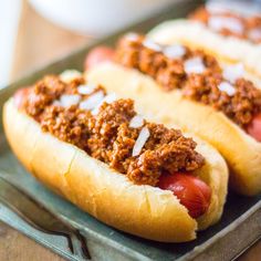 two chili dogs are sitting on a tray