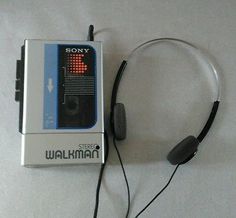 an old style walkman with headphones is laying on the floor next to it's packaging