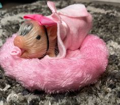 a small toy pig laying on top of a pink blanket