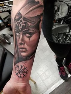 a woman's arm with a tattoo on it and a clock in the background