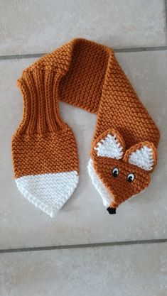 a knitted scarf with a fox head on it, sitting on a tile floor