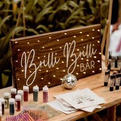 a wooden sign sitting on top of a table filled with bottles and paint tubes next to other items