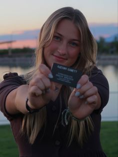 a woman holding up a business card in front of her face and pointing it at the camera