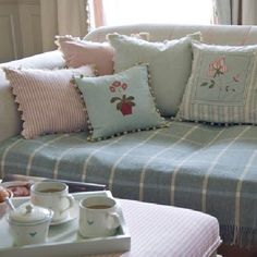 a couch with many pillows on it in front of a coffee table and window sill