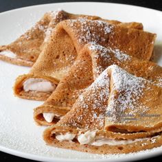 several crepes on a white plate covered in powdered sugar