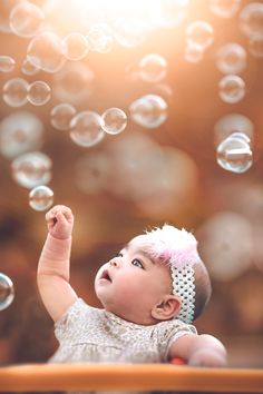 a baby is playing with bubbles in the air